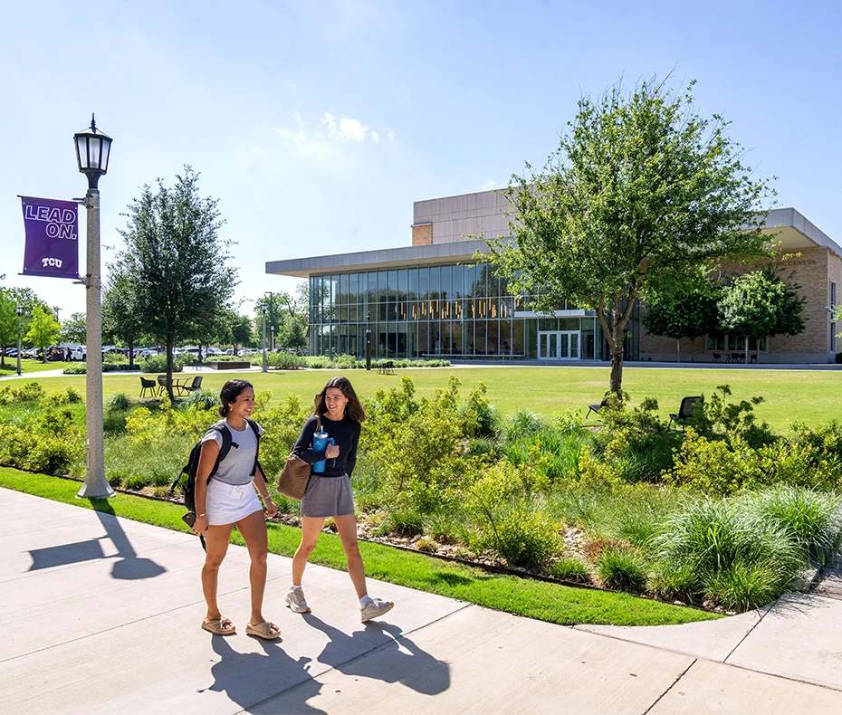 Two students chat as they walk in front of the Boschini Music Center